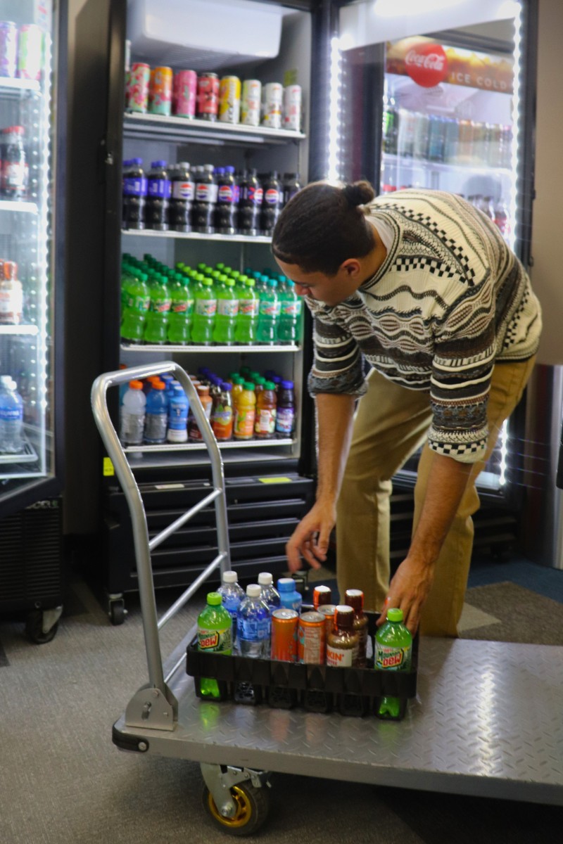 Market shelves being stocked with drinks from a service cart